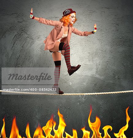 Clown balancing on a rope over fire