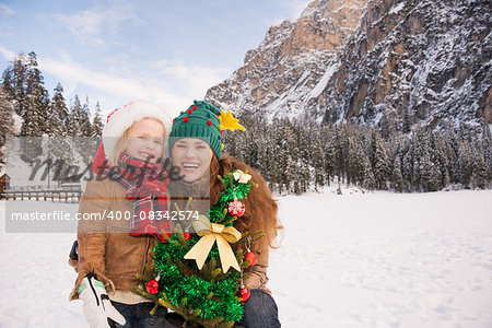 Winter outdoors on Christmas can be fairytale-maker for a children or even an adults. Portrait of smiling mother and child with Christmas tree in the front of mountains