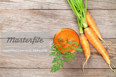 Fresh carrot juice smoothie and roots on wooden table. Top view with copy space