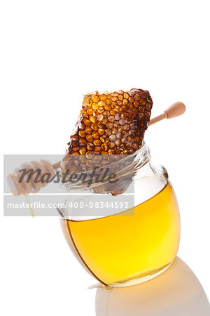 Honey in glass jar with wooden honey spoon and honey comb on white background. Healthy honey eating.
