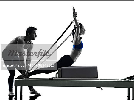 one caucasian couple exercising pilates reformer exercises fitness in silhouette isolated on white backgound