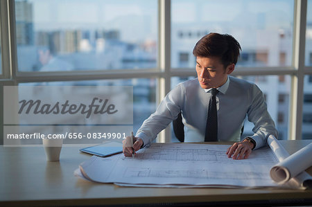 Singapore, Architect writing on building plans in office Singapore, Architect writing on building plans in office