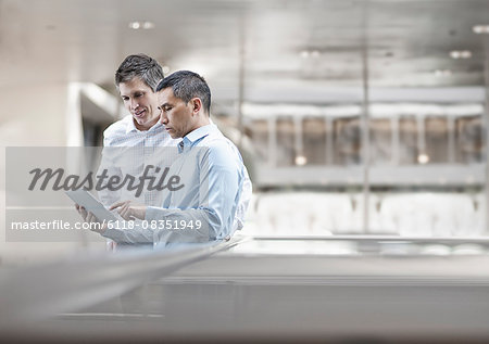 Two men, business colleagues, looking at a digital tablet screen.