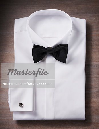 White, tuxedo shirt with a bow tie and cuff link, studio shot on wooden background White, tuxedo shirt with a bow tie and cuff link, studio shot on wooden background