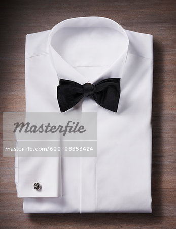 White, tuxedo shirt with a bow tie and cuff link, studio shot on wooden background