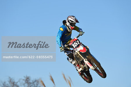 Motocross biker jumping over dirt track