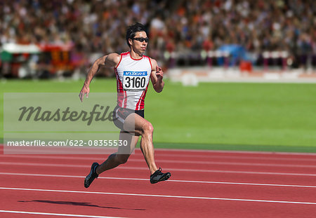 Japanese male sprinter running on track