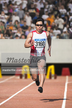 Japanese male sprinter running on track