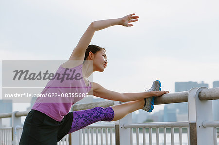 Young Japanese woman stretching before her run downtown Tokyo