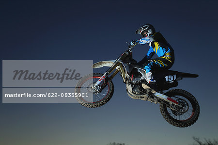 Motocross biker jumping over dirt track