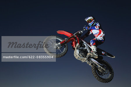 Motocross biker jumping over dirt track