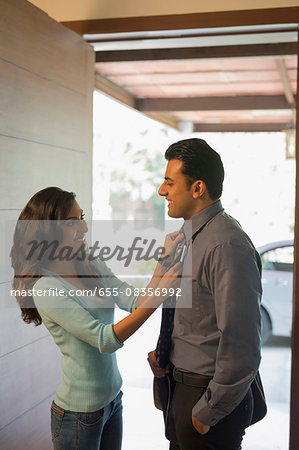 India, Woman adjusting mans tie at front door