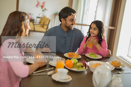 Young girl with orange juice at table with Mother and Father