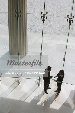 Two colleagues in glass lobby in discussion