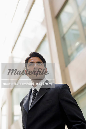 Businessman outside office building looking past camera