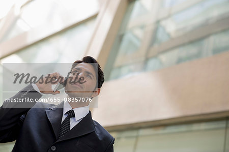 India, Businessman in suit talking on mobile phone outside office building