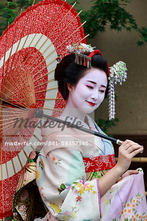 Portrait of smiling geisha in floral robes with red umbrella in summer, Kyoto, Japan, Asia