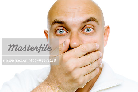 Bald blue eyes frightened man in a white jacket covers her mouth with his hand. Studio. isolated