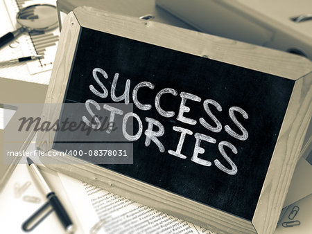 Handwritten Success Stories on a Chalkboard. Composition with Chalkboard and Ring Binders, Office Supplies, Reports on Blurred Background. Toned Image.