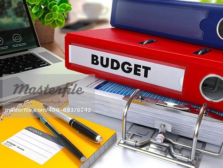 Red Ring Binder with Inscription Budget on Background of Working Table with Office Supplies, Laptop, Reports. Toned Illustration. Business Concept on Blurred Background.