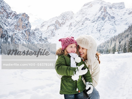 Winter outdoors can be fairytale-maker for children or even adults. Happy mother and child playing outdoors in front of snowy mountains