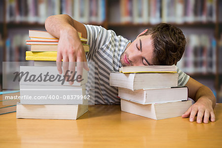 Student asleep in the library against books on desk in library