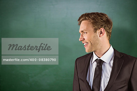 Young handsome businessman looking away against green chalkboard