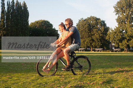 Romantic young couple on bicycle together in park