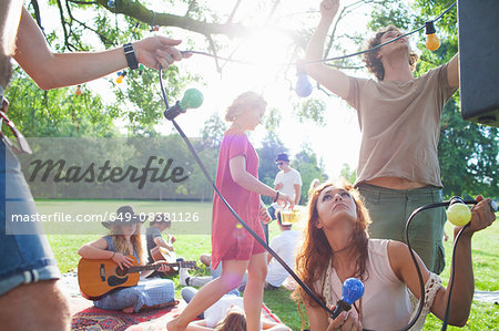 Group of friends hanging decorative lights at sunset park party