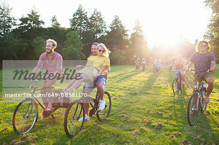 Crowd of partygoing adults arriving on bicycles to sunset park party