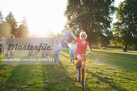 Group of partygoing adults arriving on cycles to sunset park party