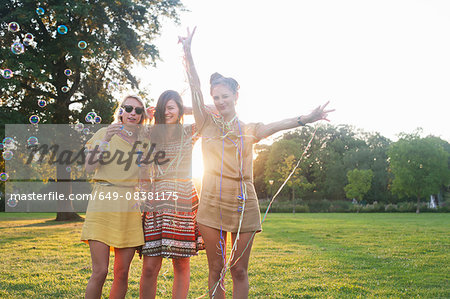 Portrait of three young women friends wrapping themselves in streamers at party in park