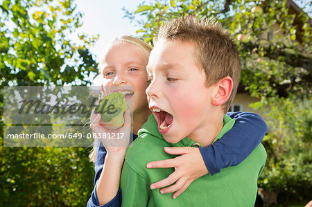 Portrait of boy and sister with picked apple from orchard