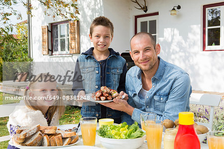 Portrait of father and children at garden barbecue table