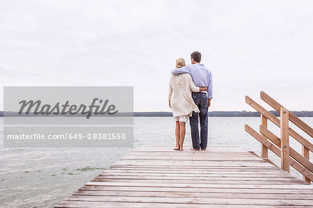 Mature couple standing on pier, looking at view, rear view