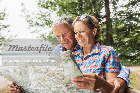 Couple in forest, looking at map, smiling Couple in forest, looking at map, smiling