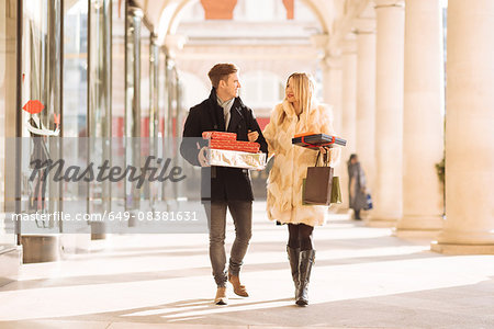Young couple carrying xmas gifts strolling in Covent Garden, London, UK