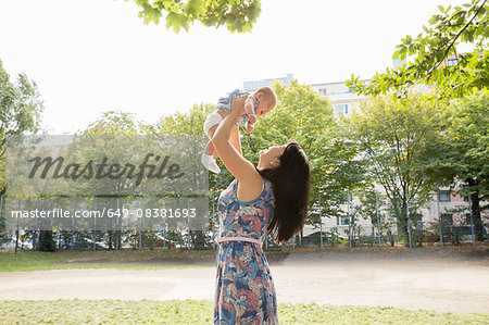Grandmother holding up baby granddaughter in park