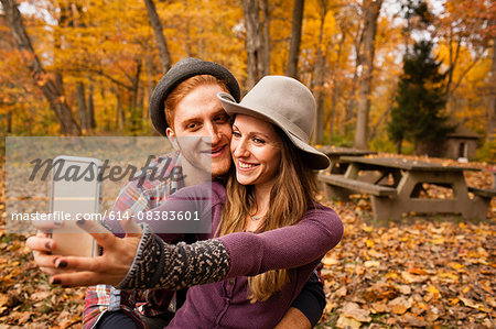 Young couple taking smartphone selfie in autumn forest