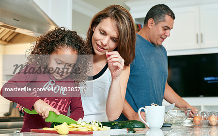 Mother helping daughter chop vegetables in kitchen