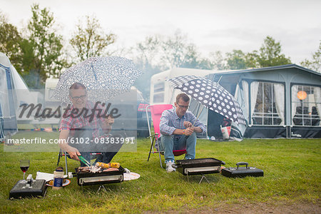 Men barbecuing in rain