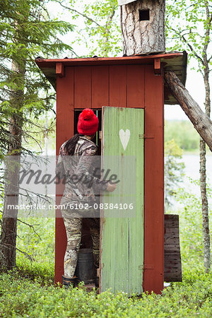 Woman entering wooden outhouse