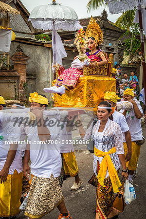 Woman being carried in a raised chair by people in a parade at a cremation ceremony for a high priest in Ubud, Bali, Indonesia