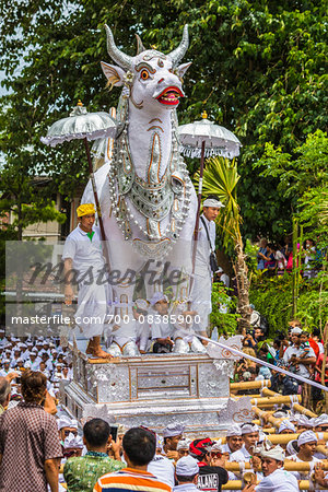 People carrying a raised, white bull character in a parade at a cremation ceremony for a high priest in Ubud, Bali, Indonesia