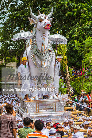 People carrying a raised, white bull character in a parade at a cremation ceremony for a high priest in Ubud, Bali, Indonesia People carrying a raised, white bull character in a parade at a cremation ceremony for a high priest in Ubud, Bali, Indonesia