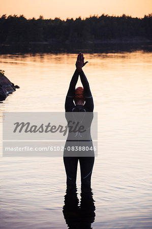 Swimmer standing in water at sunset