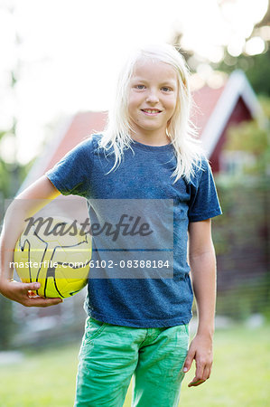 Portrait of boy with long, blonde hair holding ball