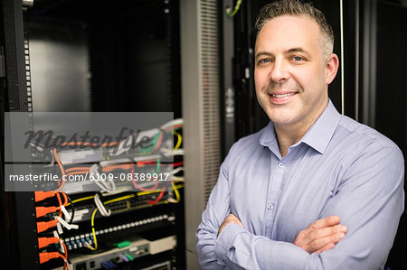 Technician smiling at camera beside server