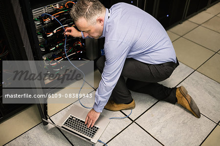 Technician using laptop to analyse server