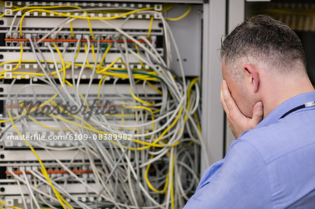 Stressed technician looking at open server locker